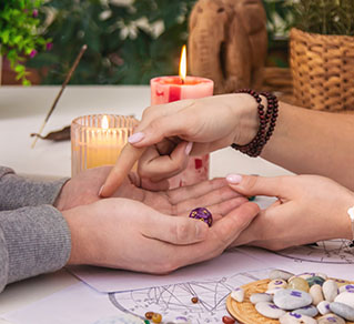 Two hands are reaching towards each other, surrounded by candles and crystals, in a serene, mystical setting.